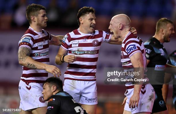Liam Farrell of Wigan celebrates his first half try with Jai Field and John Bateman during the Betfred Super League match between Wigan Warriors and...