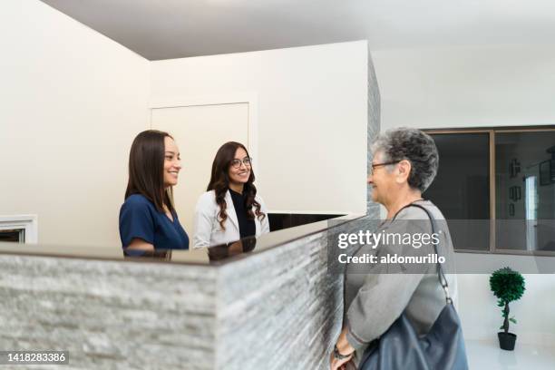 senior patient standing at dental clinic reception - waiting room clinic stock pictures, royalty-free photos & images