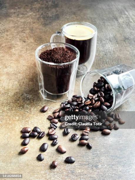 two glasses with ground coffee and coffee beans, and a shot of espresso on weathered brown background - ground coffee stock pictures, royalty-free photos & images