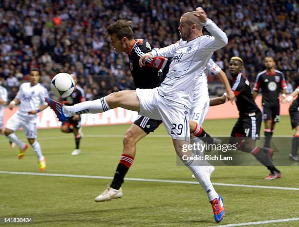 Eric Hassli of the Vancouver Whitecaps tries to get his foot on the ball while being defended by Marcelo Saragosa of D.C. United during the first...