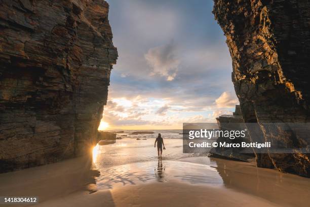 person with a camera in playa das catedrais at sunset, spain - galizien stock-fotos und bilder