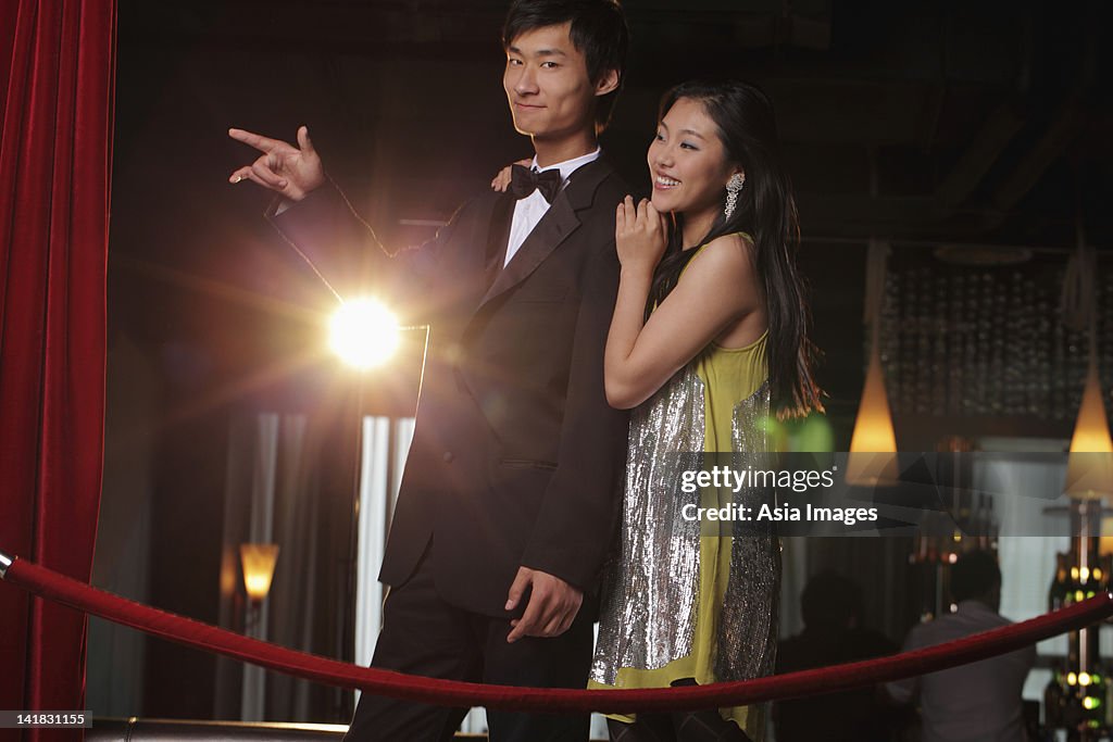Young couple standing behind red rope at night