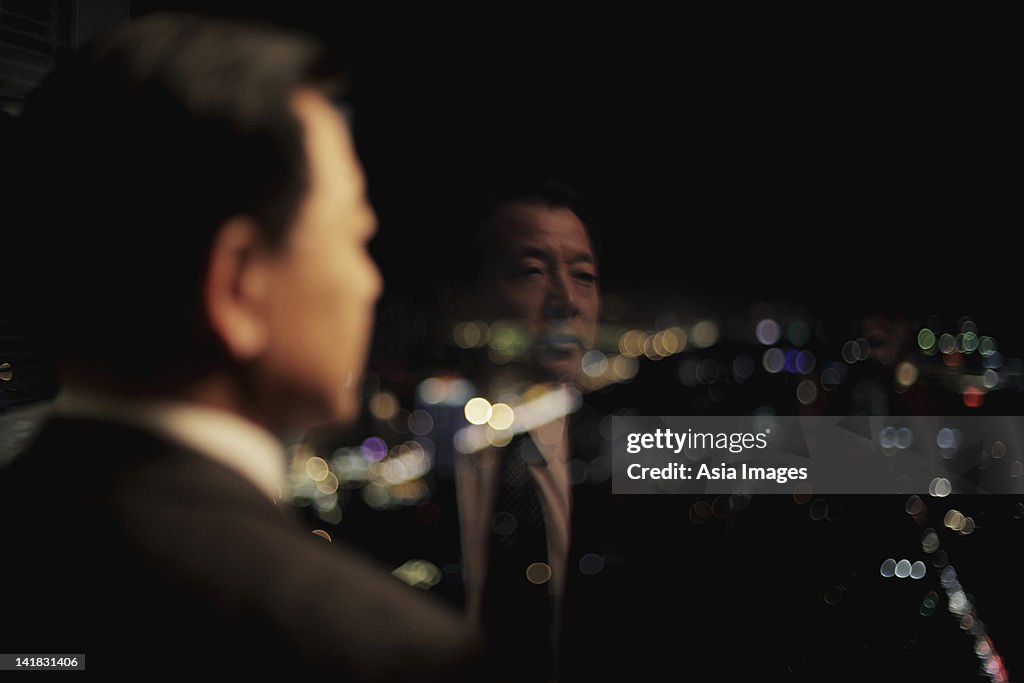 Businessman looking out of window at night