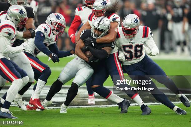 Wide receiver DJ Turner of the Las Vegas Raiders is tackled by the New England Patriots defenders during the first half of a preseason game at...