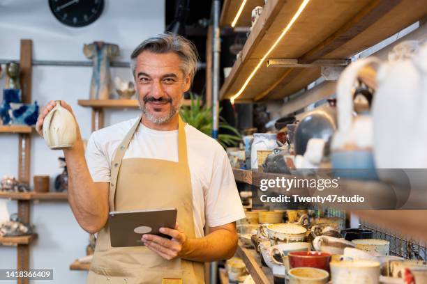 caucasian mid adult using a tablet working in the pottery store - order pad stock pictures, royalty-free photos & images