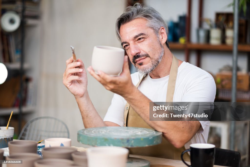 Caucasian potter artist painting a ceramic cup in the pottery studio