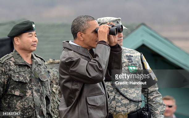 President Barack Obama uses binoculars to look at North Korea from the Observation Post Ouellette in the Demilitarized Zone which separates the two...