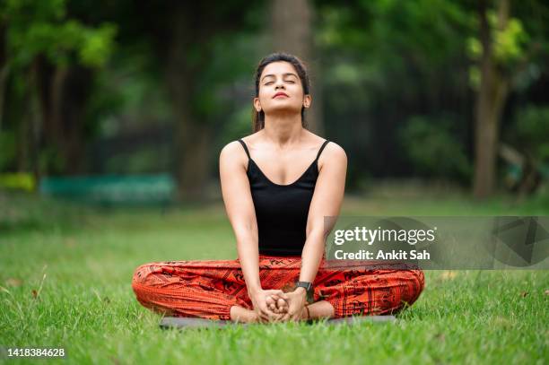 woman sitting in butterfly position with bare feet at park - sports india stockfoto's en -beelden