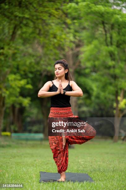 vrikshasana or tree pose exercise. athletic slim woman practicing yoga, standing on one leg in namaste position. - tree position stock pictures, royalty-free photos & images