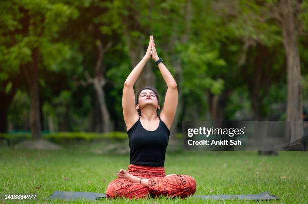 indian woman / girl performing yoga asana or meditation at park - namaste greeting stock pictures, royalty-free photos & images