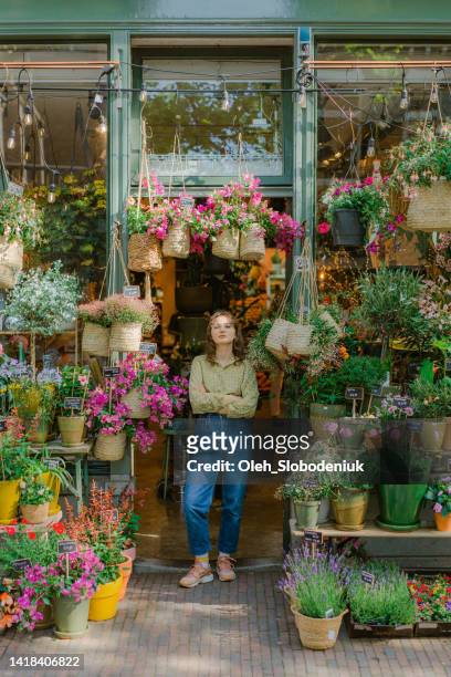 woman standing at the entrance of the flower shop - florist stock pictures, royalty-free photos & images