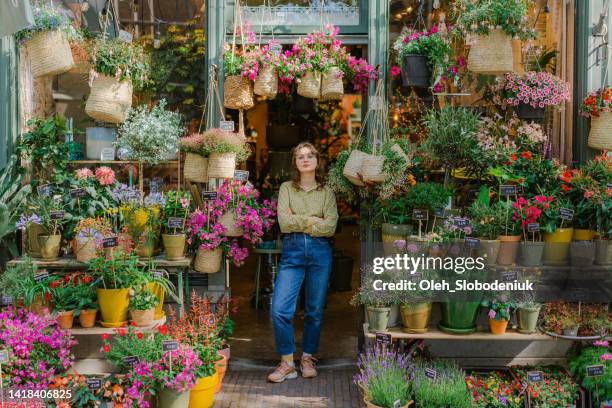 woman standing at the entrance of the flower shop - zonnescherm gebouwonderdeel stockfoto's en -beelden