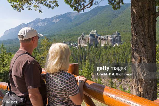 couple looking at banff springs hotel, banff, alberta, canada mr - banff springs hotel stockfoto's en -beelden