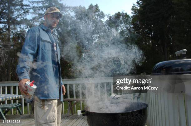 man pours lighter fluid onto bbq - lighter fluid stock pictures, royalty-free photos & images