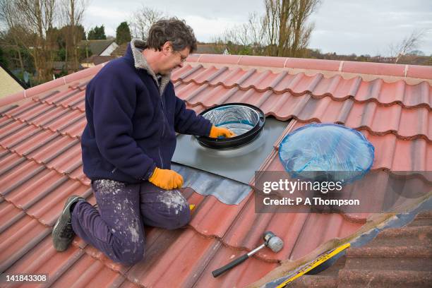 man installing a sun pipe into a tiled roof pr - skylight stock pictures, royalty-free photos & images