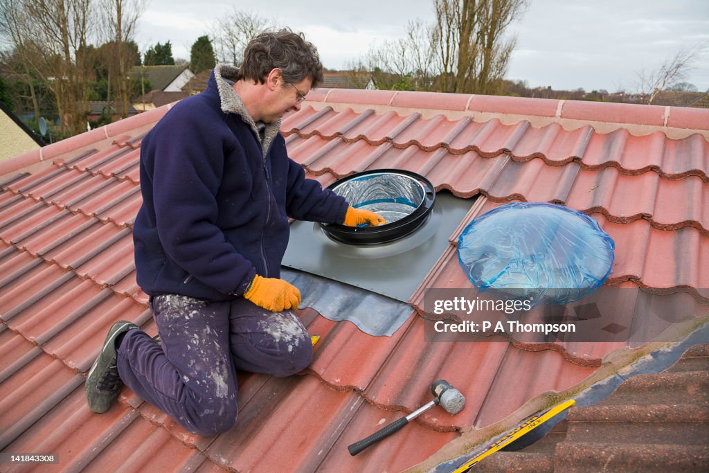 Man installing a sun pipe into a tiled roof PR