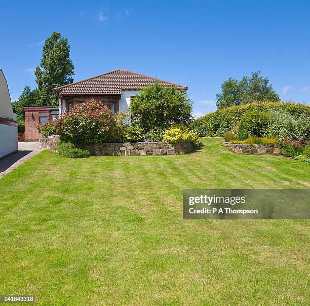 terraced border of shrubs in large garden and bungalow pr - bungalow house stock pictures, royalty-free photos & images