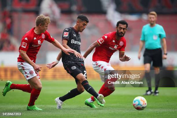 Exequiel Palacios of Bayer Leverkusen battles for possession with Jonathan Burkardt and Angelo Fulgini of 1.FSV Mainz 05 during the Bundesliga match...