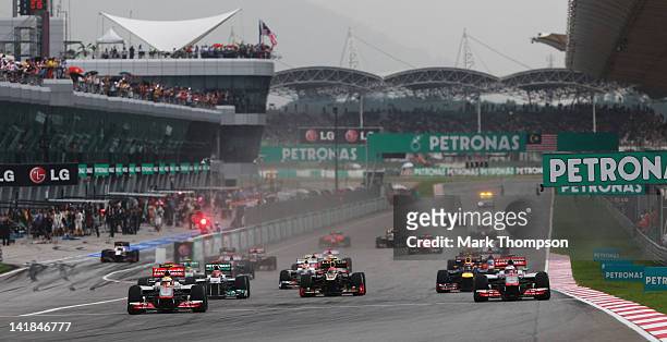 Lewis Hamilton of Great Britain and McLaren and Jenson Button of Great Britain and McLaren lead the field at the start of the Malaysian Formula One...