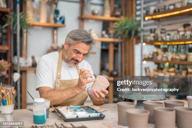 an elderly owner works on a craft pot in his ceramic studio. - konstmateriel bildbanksfoton och bilder