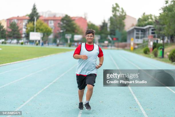 young male athlete with down syndrome running a track race - paralympics track stock pictures, royalty-free photos & images