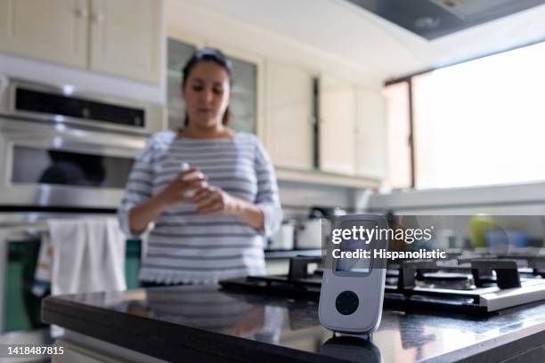 mother using a baby monitor to check on her daughter while cooking in the kitchen - baby monitor stock pictures, royalty-free photos & images