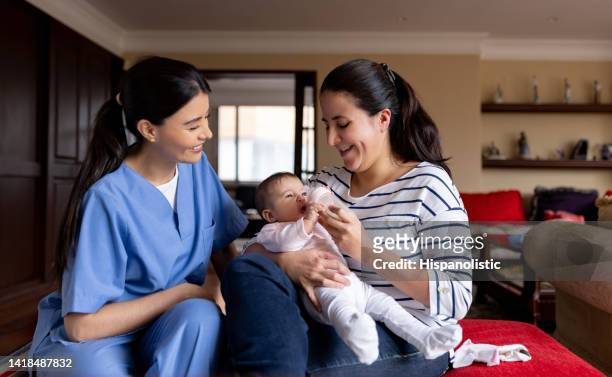 enfermera enseñando a una madre cómo alimentar a su bebé con un biberón - visita doméstica fotografías e imágenes de stock