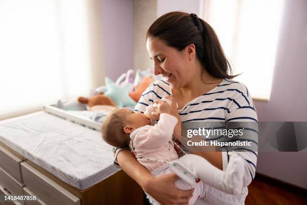 mother feeding a bottle to her baby daughter with a hip dysplasia brace - maternity leave stockfoto's en -beelden