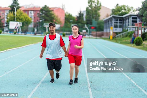 young  athletes with down syndrome running a track race - paralympics track stock pictures, royalty-free photos & images