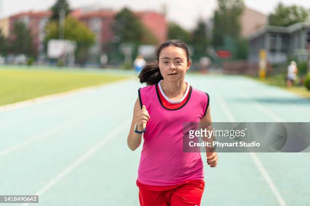 young female athlete with down syndrome running a track race - paralympics track stock pictures, royalty-free photos & images