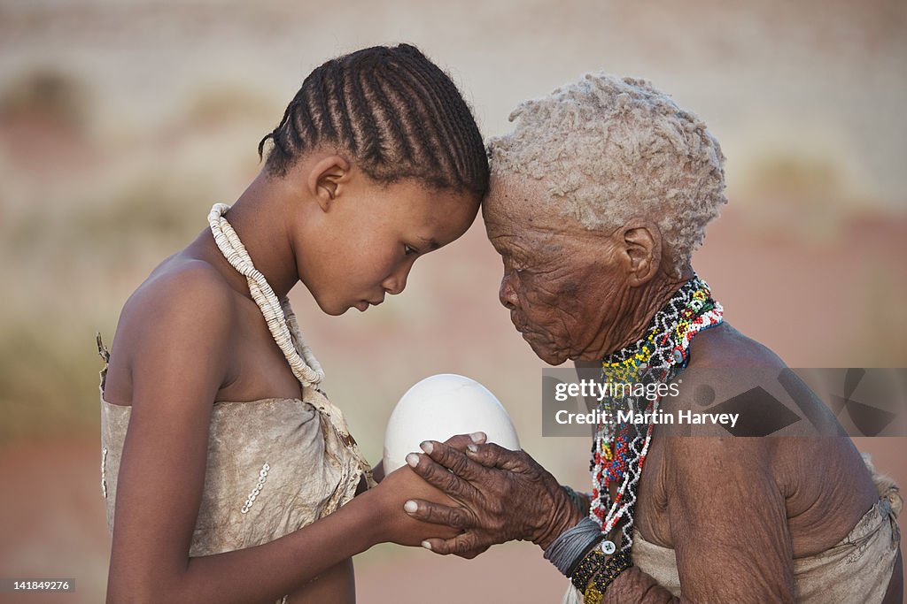 Indigenous Bushman/San girl given ostrich egg by grandmother (14years old, 75 years old), Namibia (Image taken to raise awareness and funds for the conservation pr