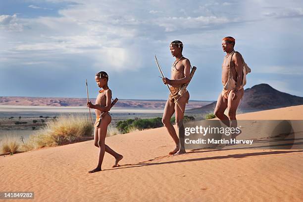 indigenous bushman/san hunters (10 years old, 43 years old, 64 years old) armed with traditional bow and arrow, namibia (image taken to raise - boxímane imagens e fotografias de stock