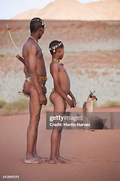 indigenous bushman/san father and son (10 years old, 43 years old) with caracal (caracal caracal) in background, namibia. (image taken to r - caracal stock pictures, royalty-free photos & images