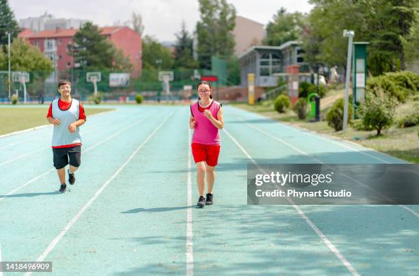 young  athletes with down syndrome running a track race - girls on train track stock pictures, royalty-free photos & images