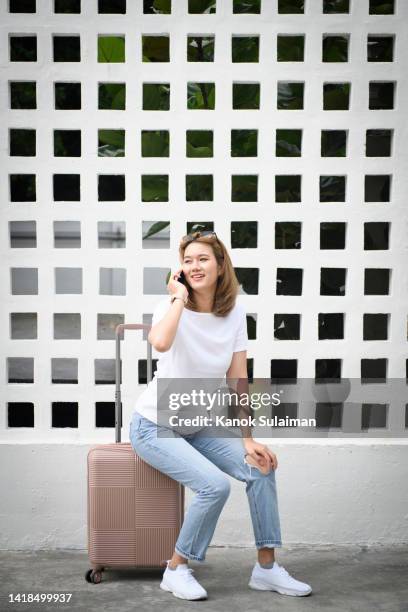young student woman sitting on suitcase and using cell phone - street fashion asian stock pictures, royalty-free photos & images