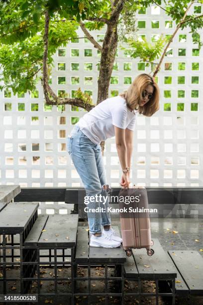 young woman pulling suitcase up stairs - carrying luggage stock pictures, royalty-free photos & images