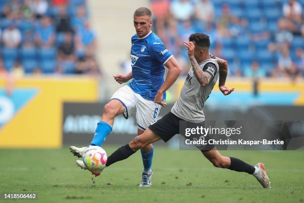 Grischa Proemel of TSG 1899 Hoffenheim is tackled by Iago Amaral of FC Augsburg during the Bundesliga match between TSG Hoffenheim and FC Augsburg at...