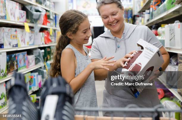 mother and daughter looking at football in store - football merchandise stock pictures, royalty-free photos & images