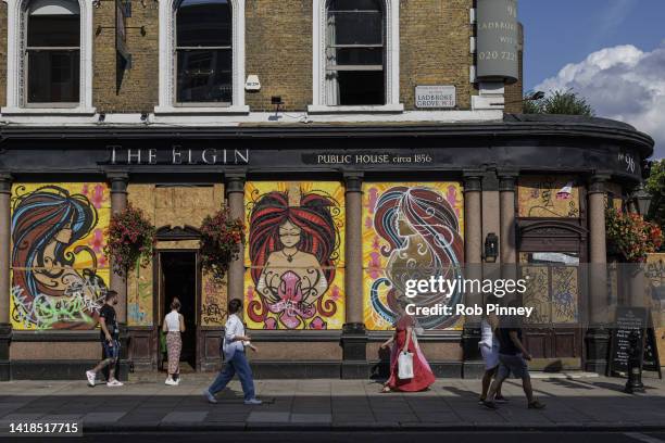 People are seen walking past a pub on Ladbroke Grove that has been boarded up ahead of Notting Hill Carnival on August 27, 2022 in London, England....
