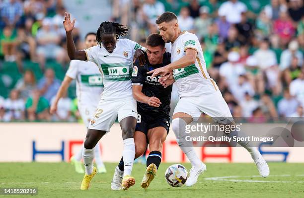 Jon Karrikaburu of Real Sociedad competes for the ball with Domingos Quina and Lucas Boye of Elche CF during the LaLiga Santander match between Elche...