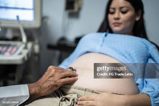 gynecologist checking pregnant woman with stethoscope at his office - human reproductive organ stock pictures, royalty-free photos & images