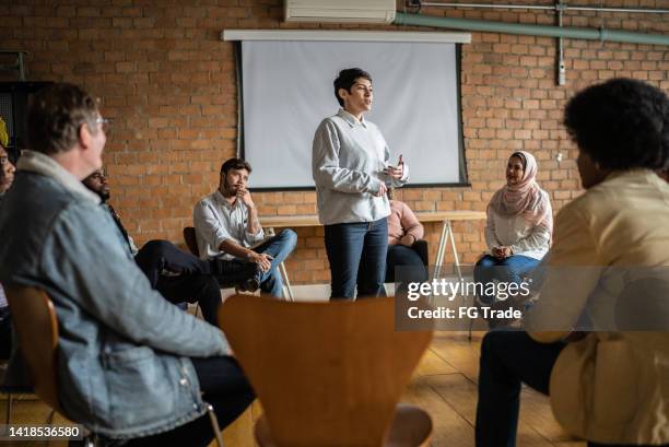 mulher nova dando uma palestra em uma universidade ou terapia de grupo - voz - fotografias e filmes do acervo