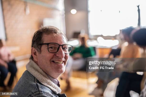 portrait of an adult student sitting in the classroom or group therapy or seminar - boss over shoulder stock pictures, royalty-free photos & images