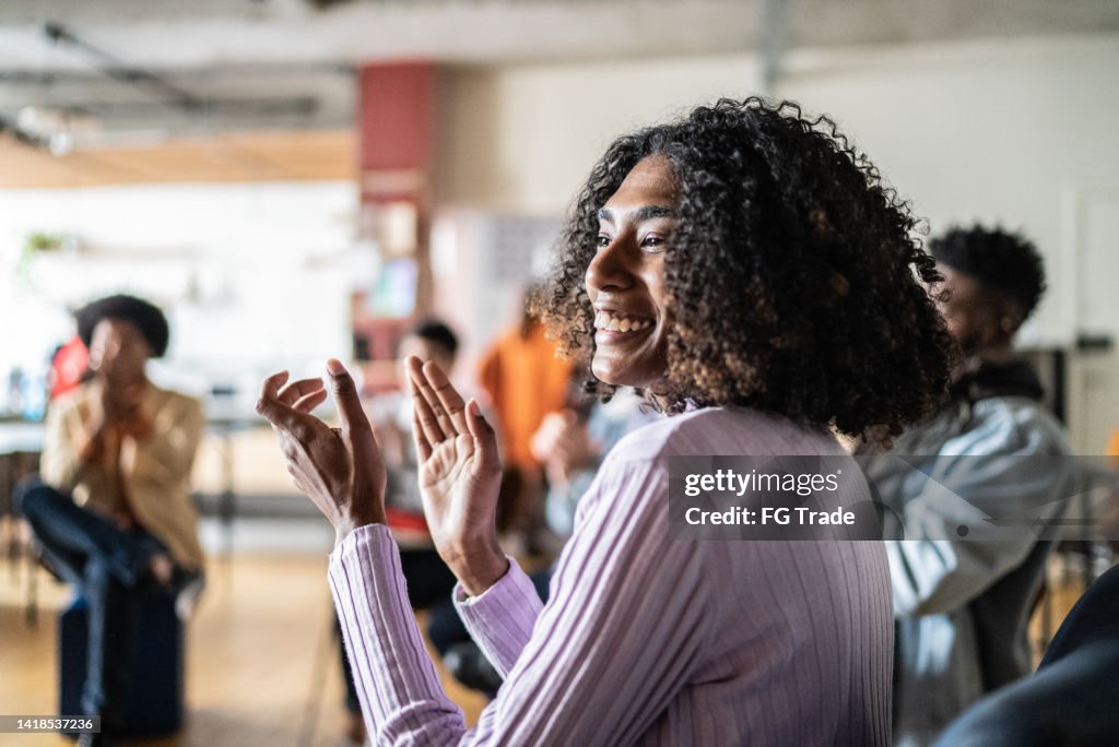 Young woman clapping in a seminar or group therapy