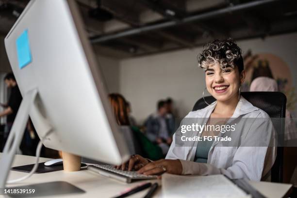portrait of a young woman using the computer in the office - gender equality stockfoto's en -beelden