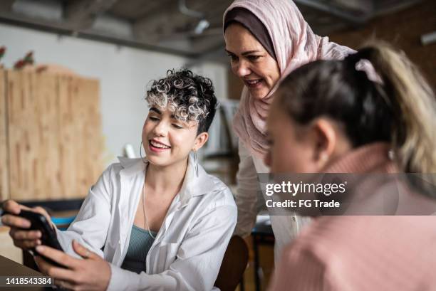 insegnante che parla con gli studenti in classe usando il telefono cellulare - compresa la donna con bisogni speciali - abbigliamento religioso foto e immagini stock