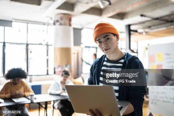 portrait of a young man holding the laptop in the classroom or small business - university student portrait stockfoto's en -beelden