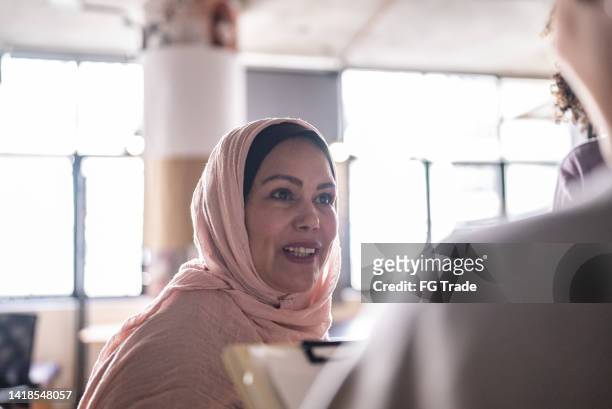 mature woman talking with colleagues in the classroom or networking event - arab community life bildbanksfoton och bilder