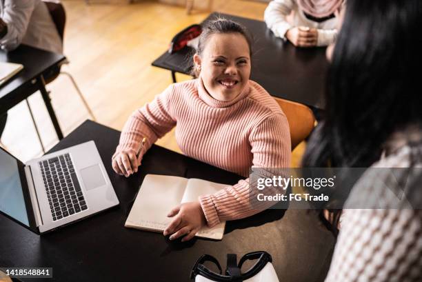 young woman with special needs talking to teacher in the classroom - special education stock pictures, royalty-free photos & images