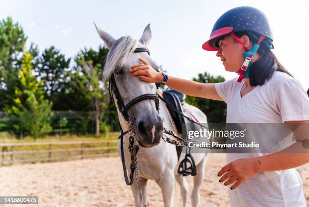 happy young girl with down syndrome caressing horse - horse riding stockfoto's en -beelden